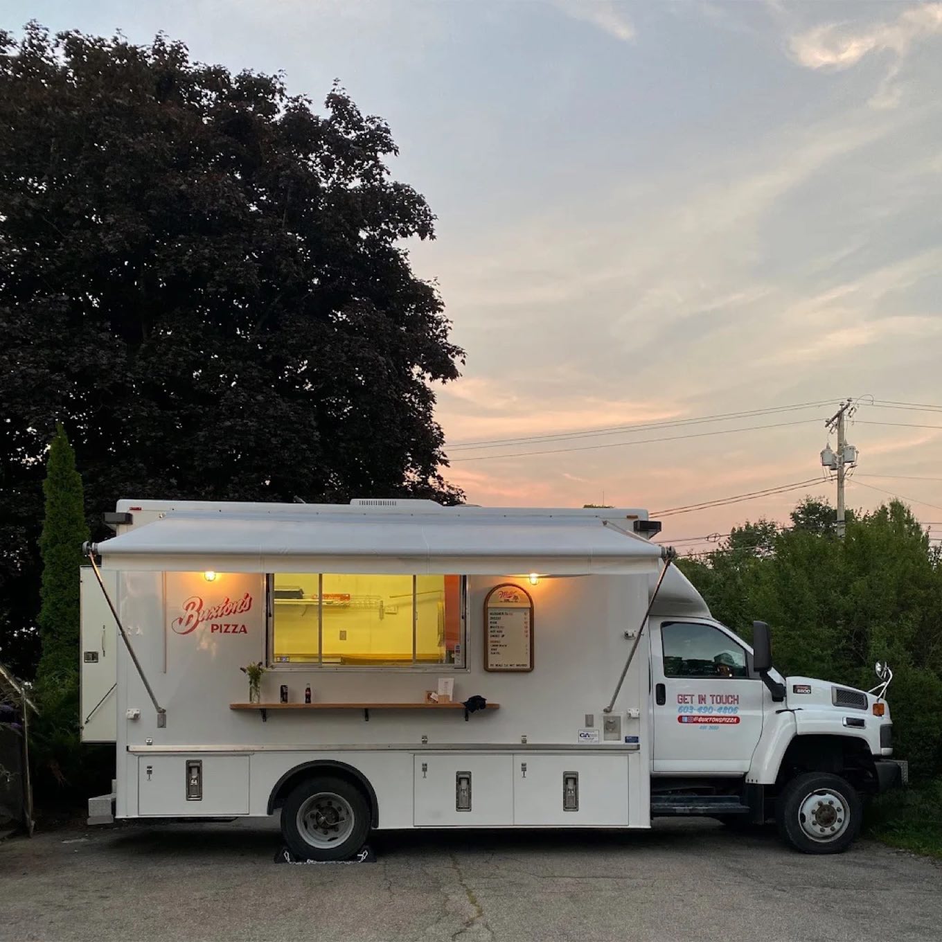 The Buxton's truck at golden hour, awning up and the service window glowing